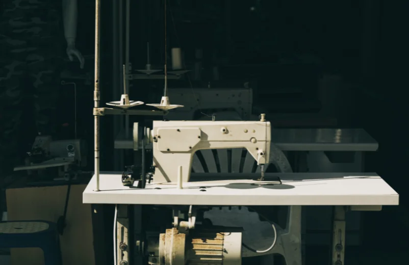 Industrial sewing machine standing alone on its table in a dim workshop
