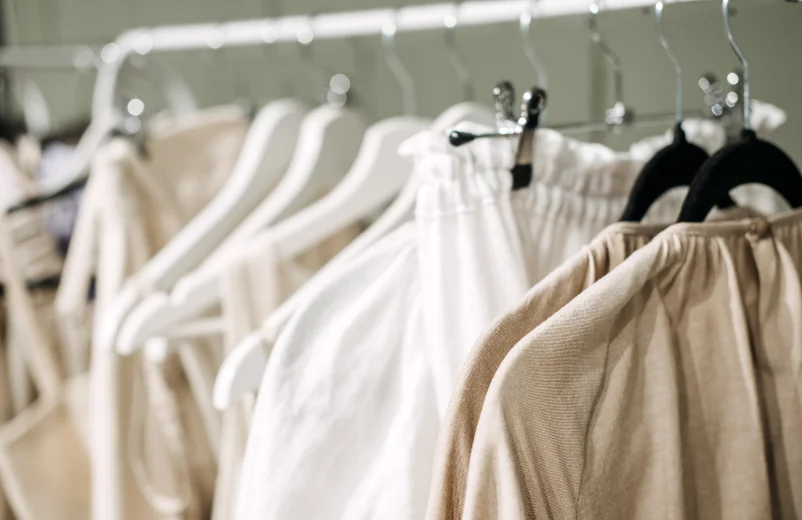 Rack of cream and white garments hanging on wooden hangers