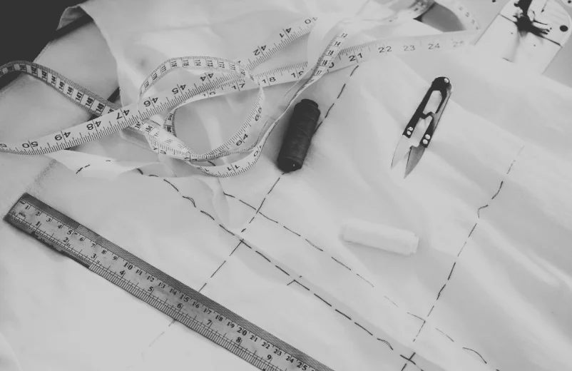 Pattern marked on fabric with a measuring tape, a ruler and thread snips, black and white photo