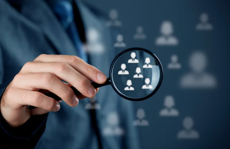 Magnifying glass over customer icons, representing target audience research