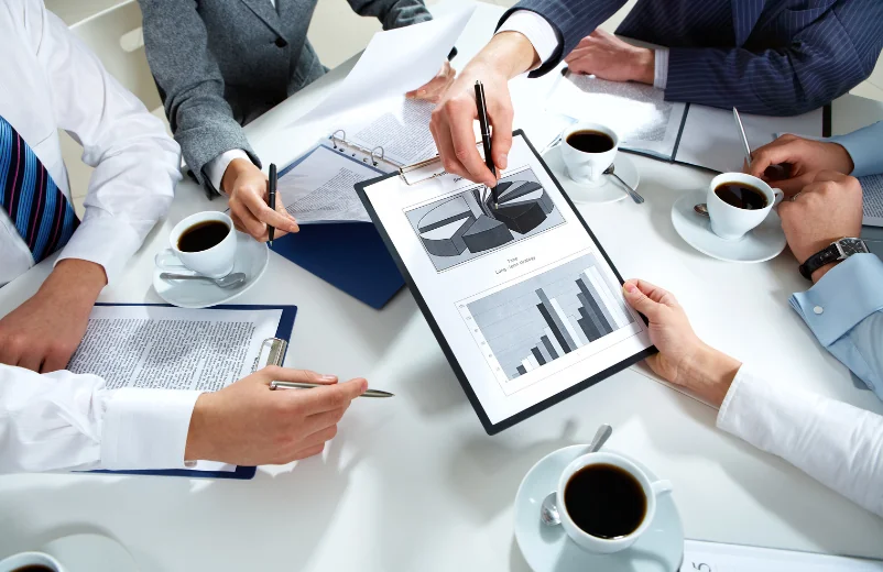 Business team reviewing charts and reports around a meeting table