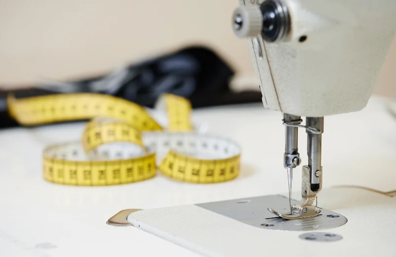 Sewing machine needle with a yellow measuring tape on the work table
