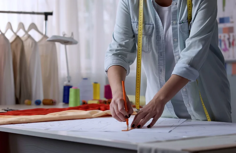 Pattern maker tracing a pattern on paper at a cutting table