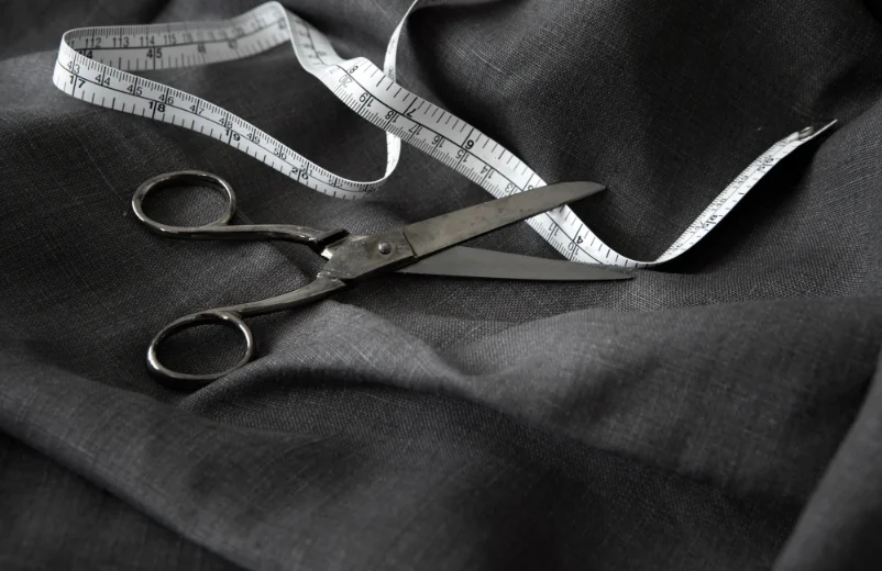 Tailor's shears and a measuring tape on black fabric