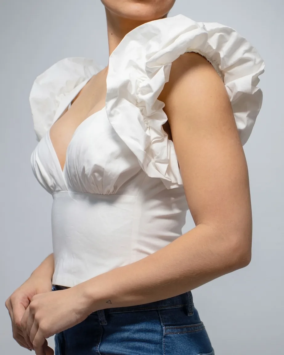 Close-up of white puff sleeve over blue jeans, GAT tailoring detail.