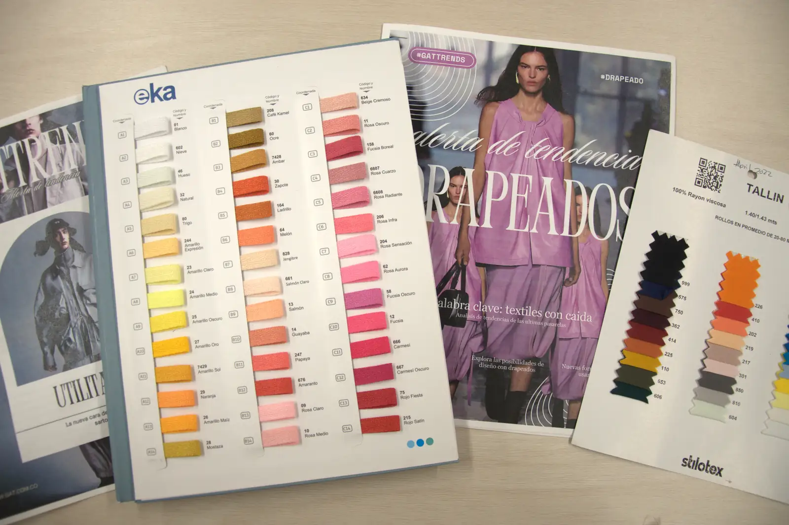 Color chart, fabric swatch card and a runway trend magazine on the GAT design table