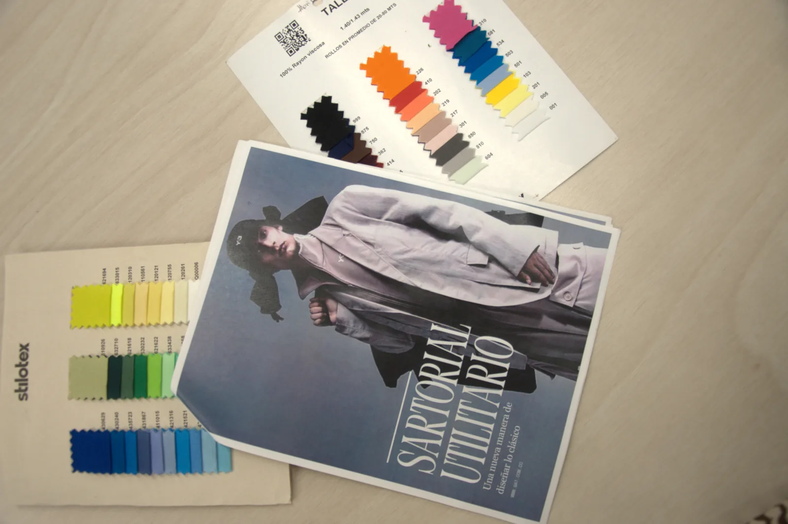 Designer drawing a dress on a laptop with fabric swatches on the development table