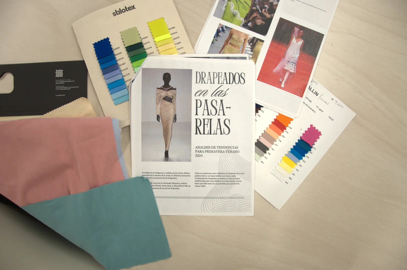 Muestras de tela y revista de tendencias sobre la mesa de desarrollo de producto