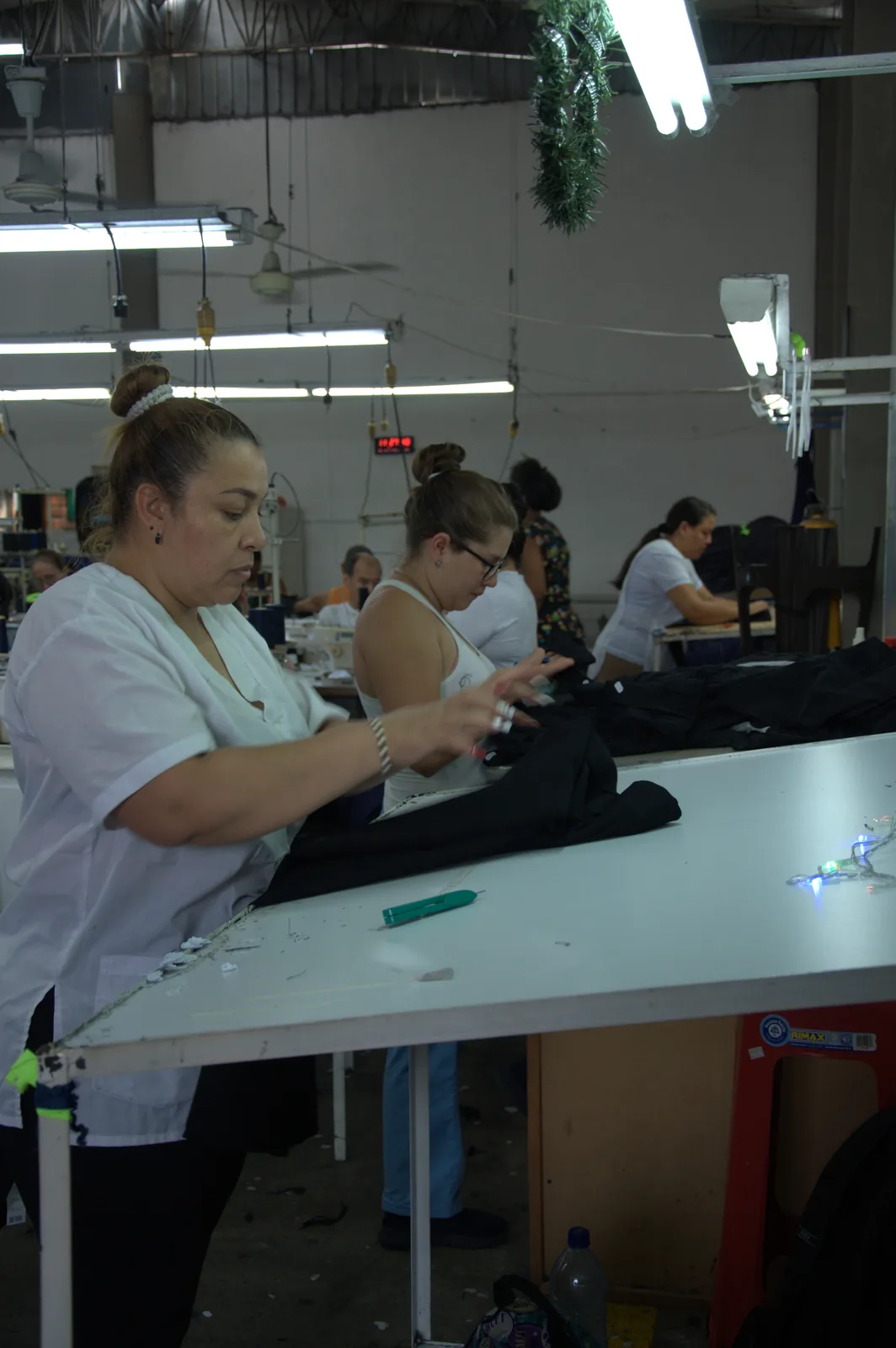 Garment worker inspecting a finished black garment at the quality control worktable