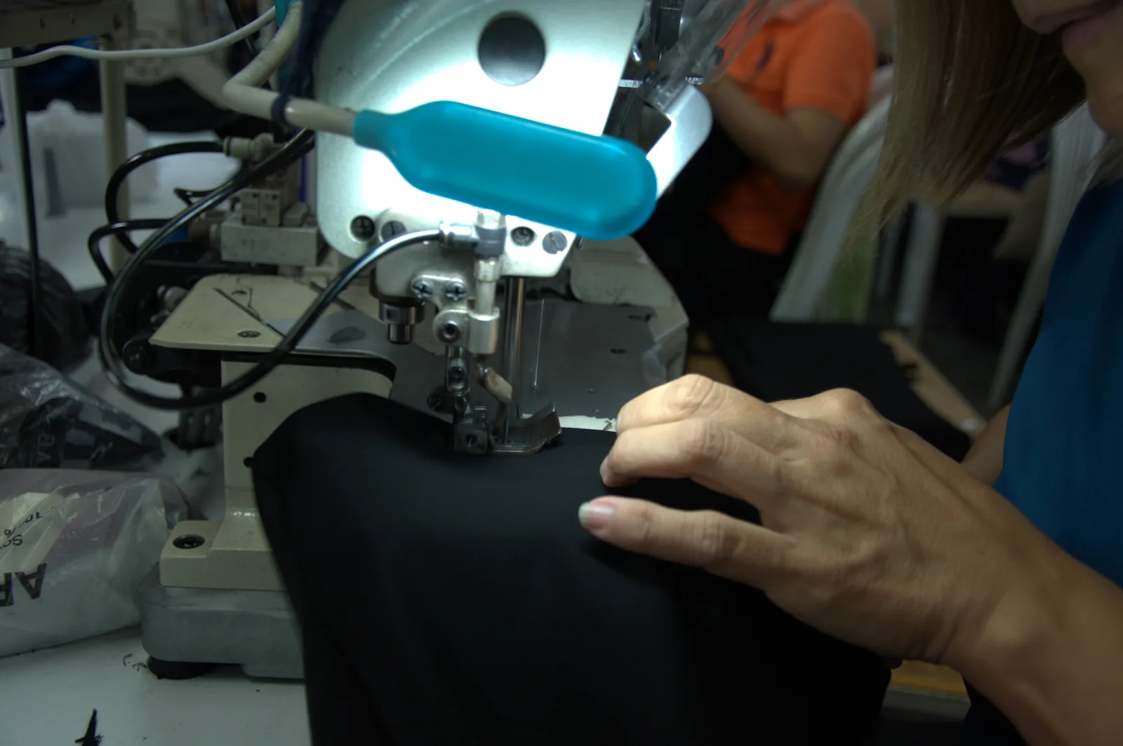 Operaria guía tela negra bajo prensatelas de máquina de coser