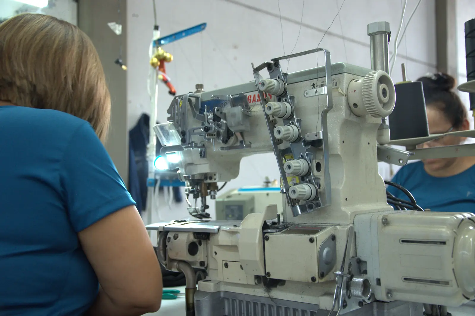 Worker operating Pegasus coverstitch machine at GAT garment factory