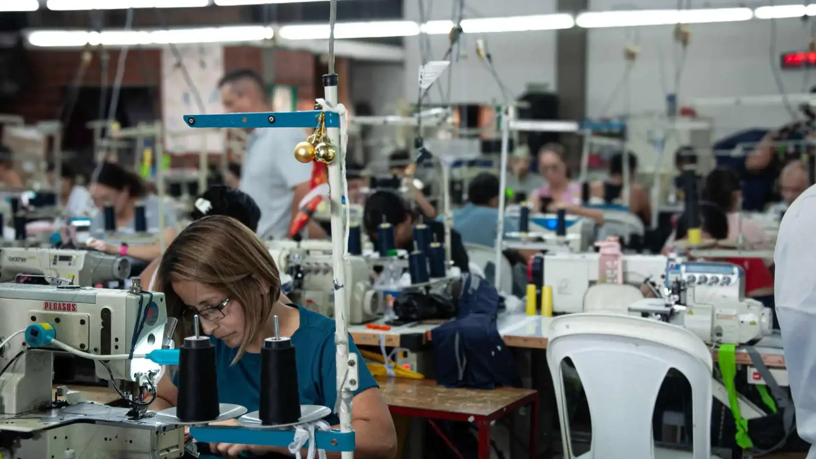 Worker sewing on Pegasus machine at GAT garment factory floor