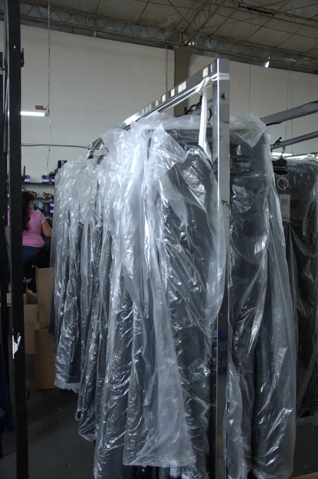 Finished dark garments wrapped in protective plastic hanging on the dispatch rack