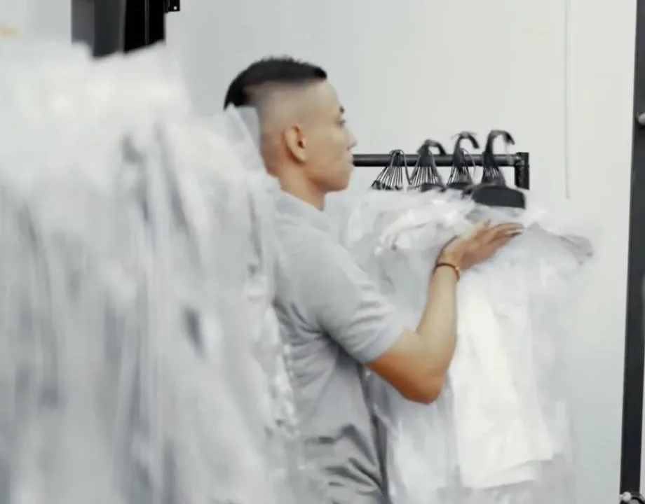 Trabajador revisando prendas terminadas cubiertas en plástico protector en planta GAT
