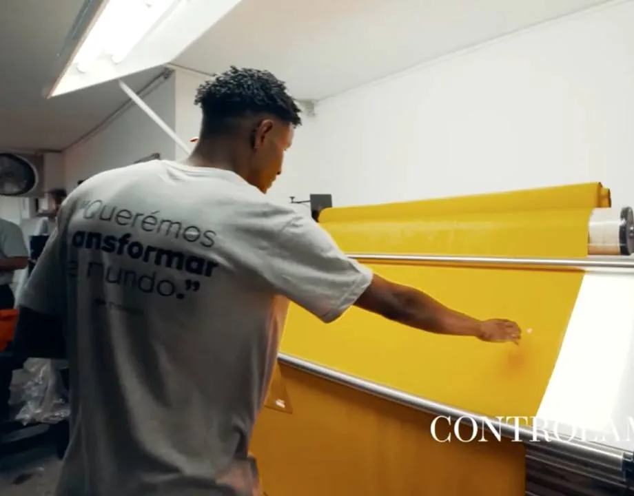 Worker inspecting a roll of yellow fabric on the incoming quality control machine